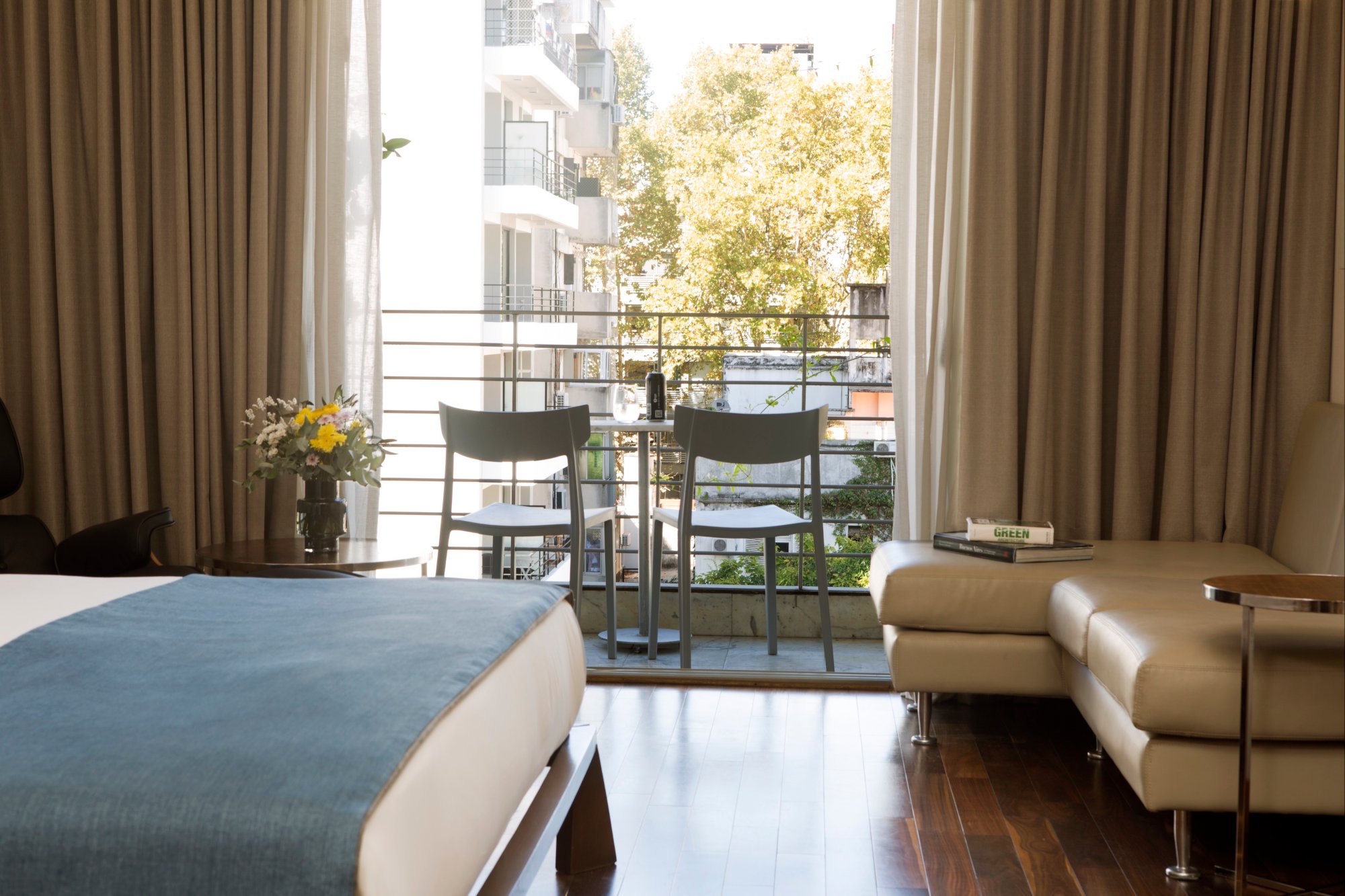 Balcón privado de una habitación Deluxe con dos sillas y vistas verdes