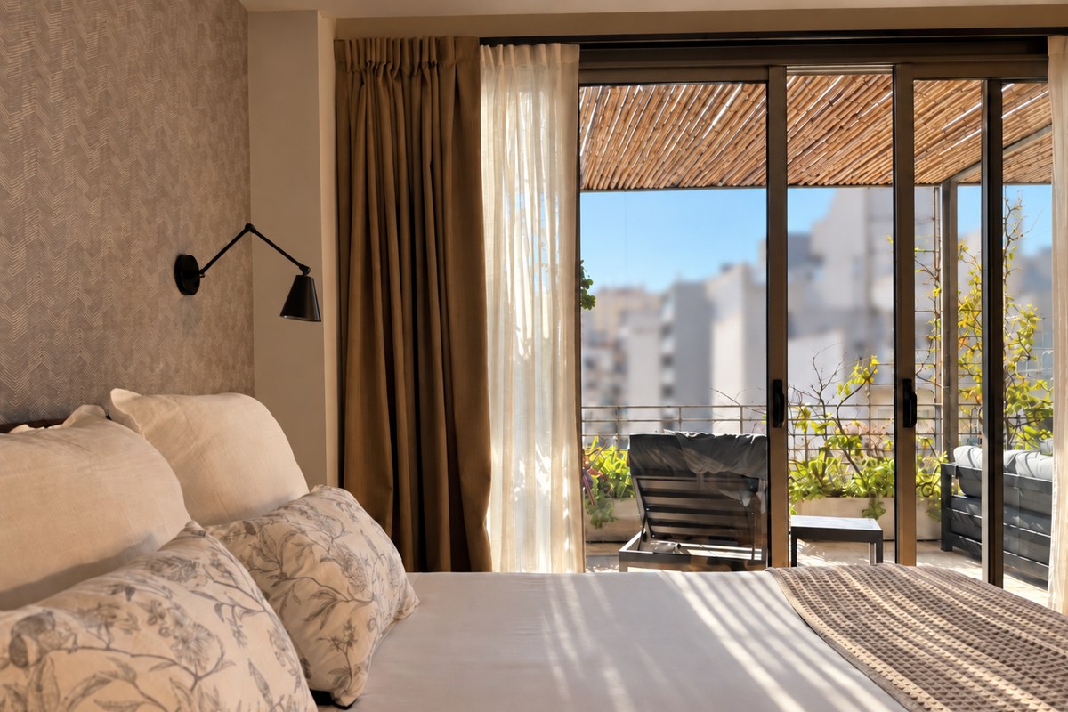 Cama de la Suite Terrace con las puertas corredizas abiertas a la terraza privada